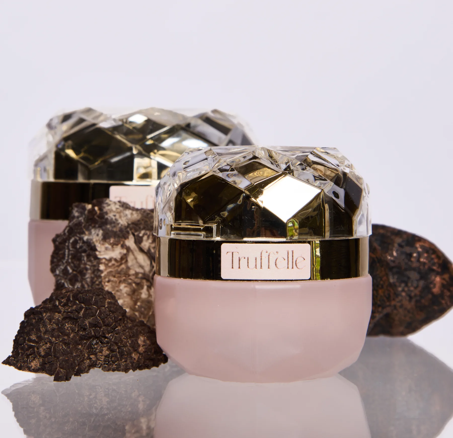 The Truff'elle face and eye cream jars beside fresh black truffles